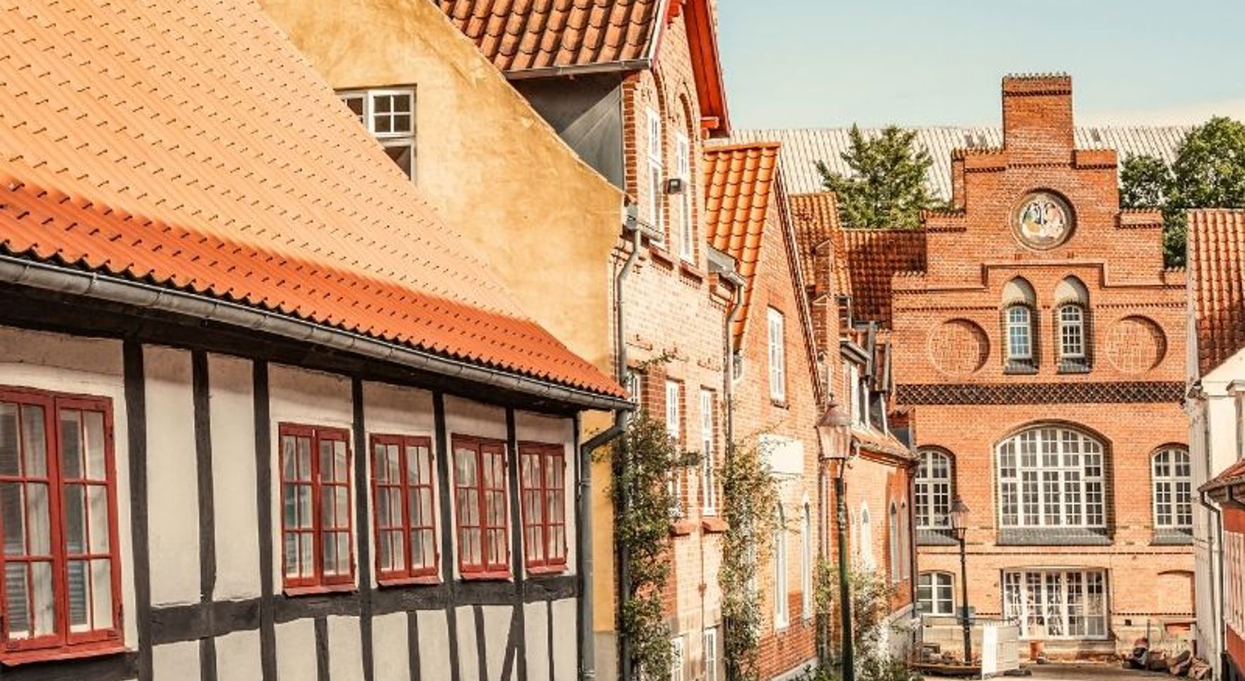 En hyggelig brostensgade i Viborg med et bindingsværkshus badet i aftensol